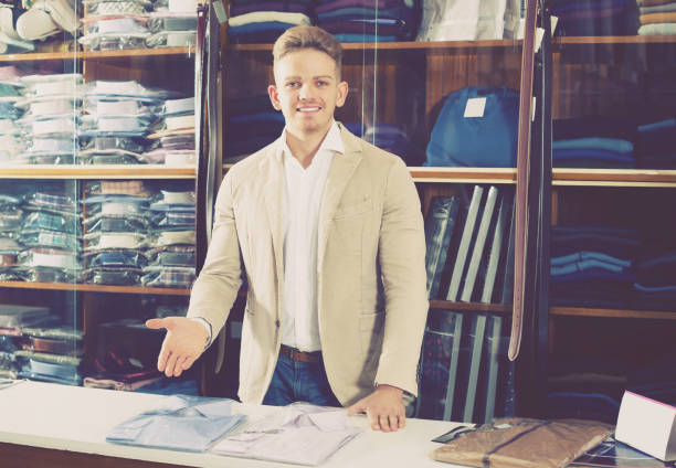 istock Young male shopping assistant offering shirts 910538772