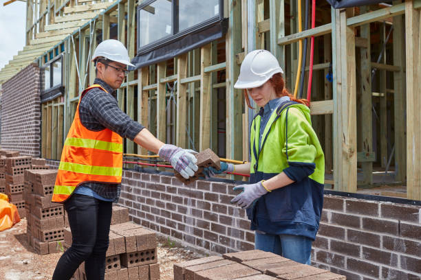 istock Male giving bricks to female for stacking at site 910546770