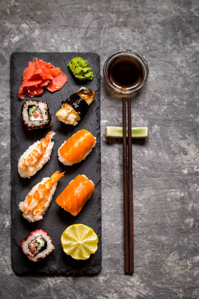 istock sushi and sushi rolls, sushi nigiri on stone plate on dark background, mustard wasabi 910547310