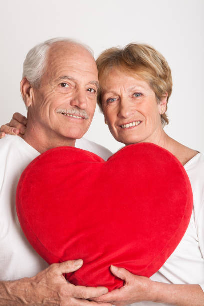 istock senior couple holding a heart shaped cushion 910559692