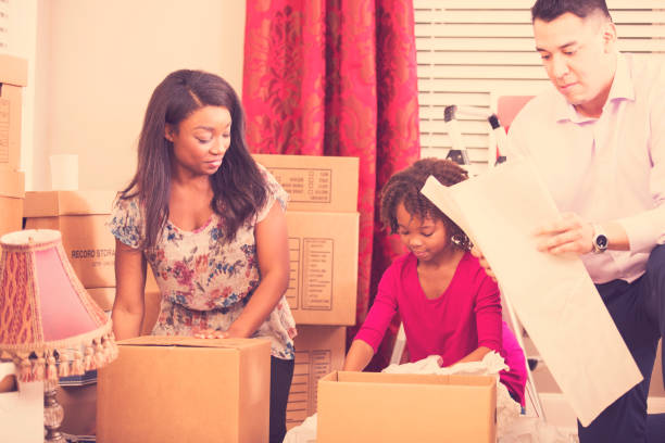 istock Multi-ethnic family packs, unpacks moving boxes in new home. 910560080