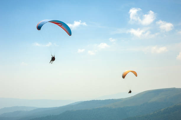 istock Two paragliders fly over a mountain valley on a sunny summer day. 910572540