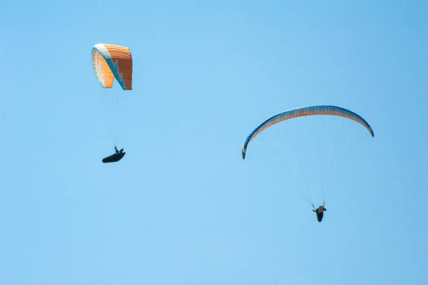 istock Two paragliders flying on the background of blue sky. 910572550