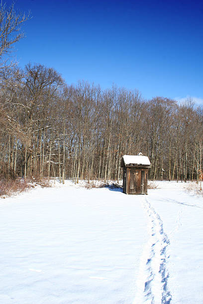 This is a wide angle view of an old fashioned, wooden outhouse by a dirt trail on a summer day in Central Florida.