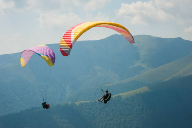 istock Two paragliders fly over a mountain valley on a sunny summer day. 910574760
