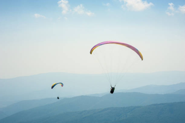 istock Two paragliders fly over a mountain valley on a sunny summer day. 910574804