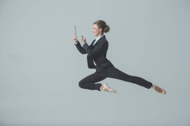 ジャンプとデジタル タブレットを使用してスーツとバレエ シューズの女性実業家 - jumping business women dancing ストックフォトと画像