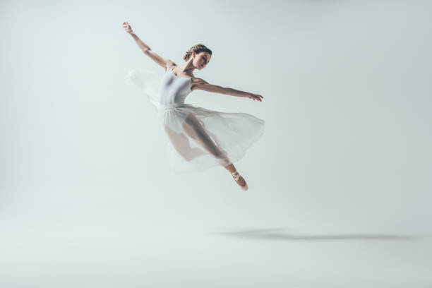 elegante ballett-tänzerin im weißen kleid springen im studio - balletttänzer stock-fotos und bilder