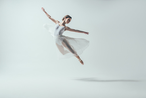 bailarina elegante en vestido blanco saltando en el estudio photo
