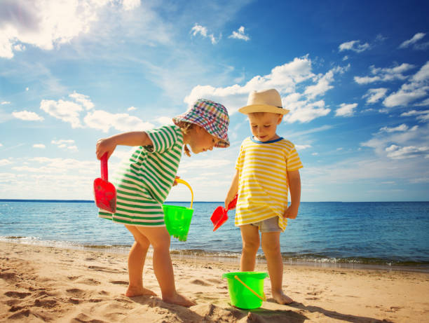 jungen und mädchen spielen auf den strand - lifestyles child beach digging stock-fotos und bilder