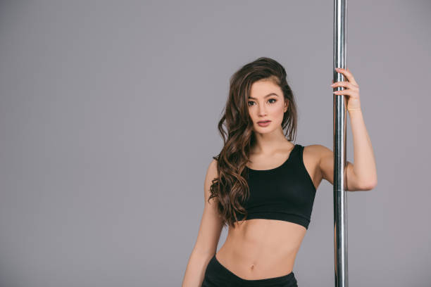 istock woman standing near pole and looking at camera on grey 910596464