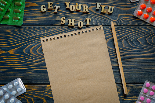 Get Your Flu Shot a text wooden letters on a dark table, the thermometer with high temperature, the top view, the place for your text. Receive the help in time.