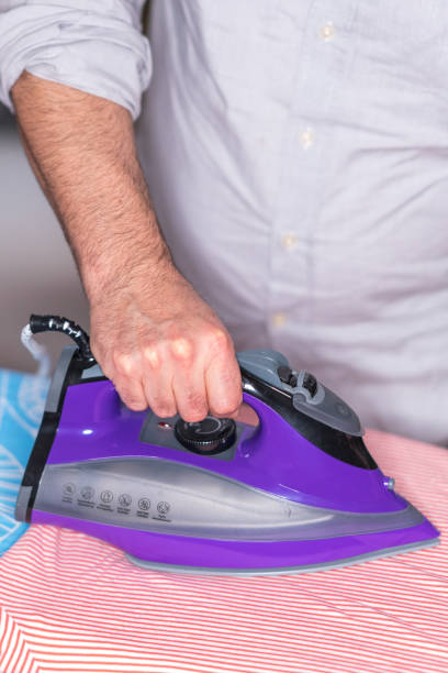 istock Cropped image of male hand ironing clothes 910597082