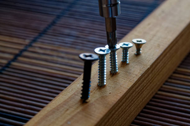 istock Scattered screw screwed with screwdriver into the wooden plank 910599344