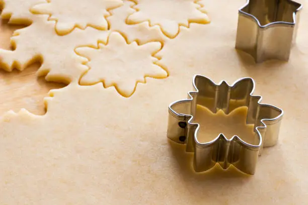 Preparation of traditional Linzer Christmas cookies - cutting out star shapes from rolled out dough
