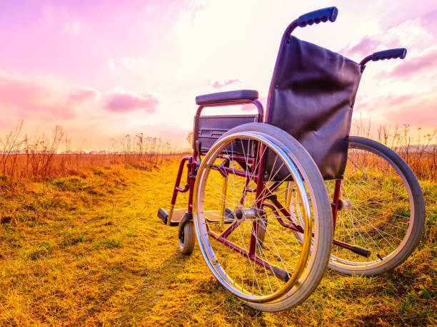 Empty wheelchair on the meadow at sunset Empty wheelchair on the meadow at sunset. Miracle concept. Healed person raised and went away buddhist prayer wheel stock pictures, royalty-free photos & images