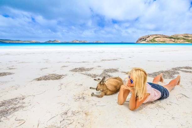 Happy woman lying on pristine white sand of Lucky Bay near Kangaroo. Cape Le Grand National Park, Esperance, Western Australia. Female tourist enjoys one of the most paradisiacal Australian beaches.