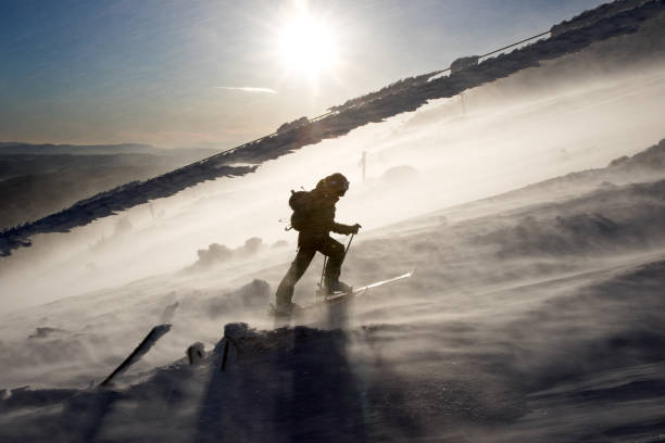 Back country skier climbing a mountain in a severe storm.
