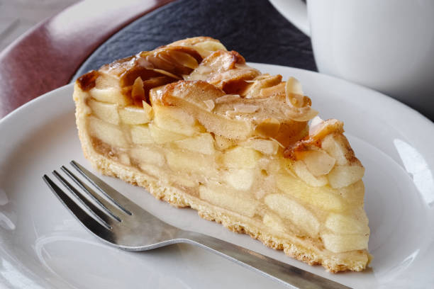 istock A slice of apple pie on white ceramic plate with fork. Black and brown table. 910616572