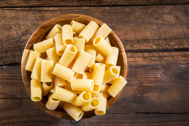 pastas crudas mezzi rigatoni en madera - rigatoni fotografías e imágenes de stock