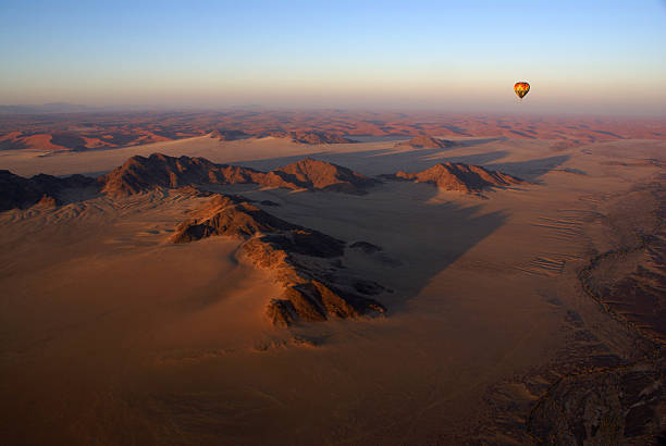 flight with hot air balloon over Marrakech at sunrise, aerial view of desert and High Atlas Mountains