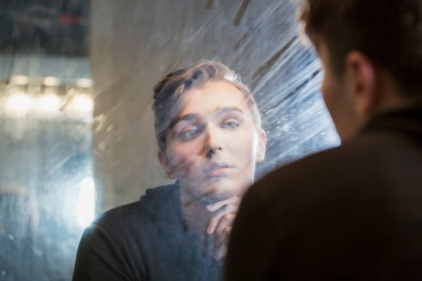 istock Serious young man in dressing room staring at reflection 910634020