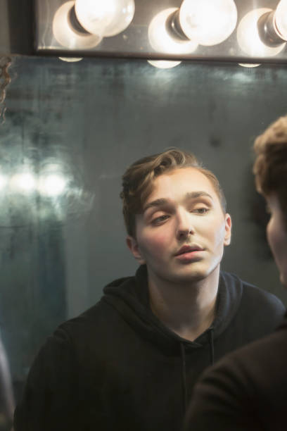 istock Serious young man in dressing room staring at reflection 910634032