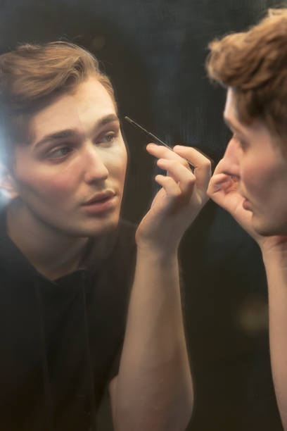 istock Young man in dressing room applying make-up 910634110