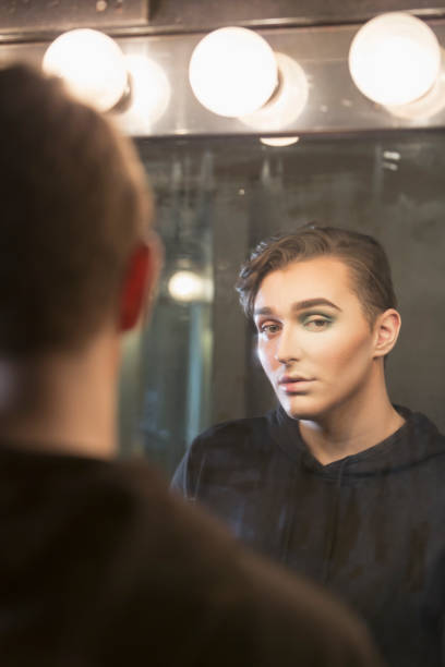 istock Young man at dressing room mirror, with make-up 910634192