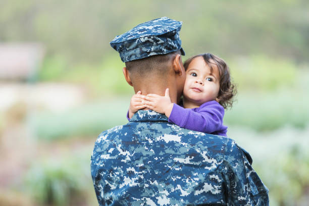 US military man with baby girl Military homecoming: A young mixed race man serving in the military, with his young daughter, 16 months old. us navy stock pictures, royalty-free photos & images