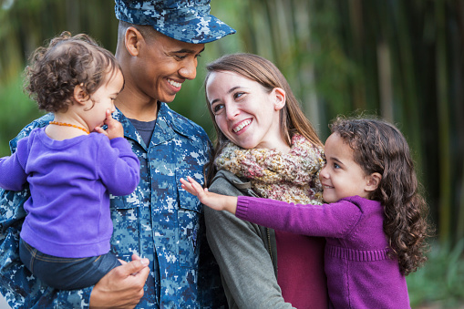 Military homecoming: A young mixed race man serving in the navy with his young family.
