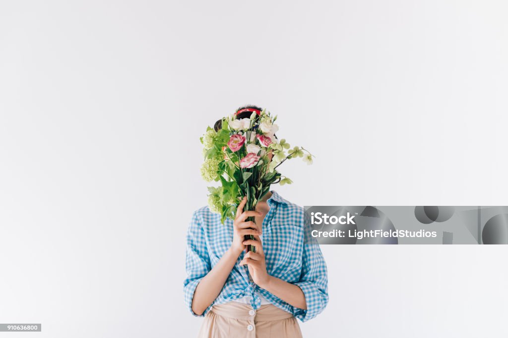 woman covering face with flowers obscured view of woman covering face with bouquet of flowers isolated on grey Flower Stock Photo