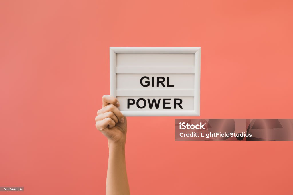 board with girl power lettering partial view of female hand holding board with girl power lettering isolated on orange Girl Power Stock Photo