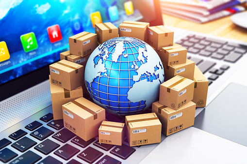 Creative abstract shipping, delivery and logistics technology business industrial concept: 3D render illustration of the macro view of heap of stacked corrugated cardboard package boxes and blue Earth globe with with world map on computer PC laptop notebook keyboard with selective focus effect