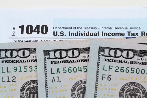 One hundred dollar bills on top of 1040 IRS tax return form