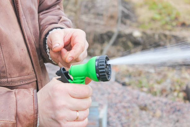 istock Man turns on the hose for watering plants with a sprayer. 910655140