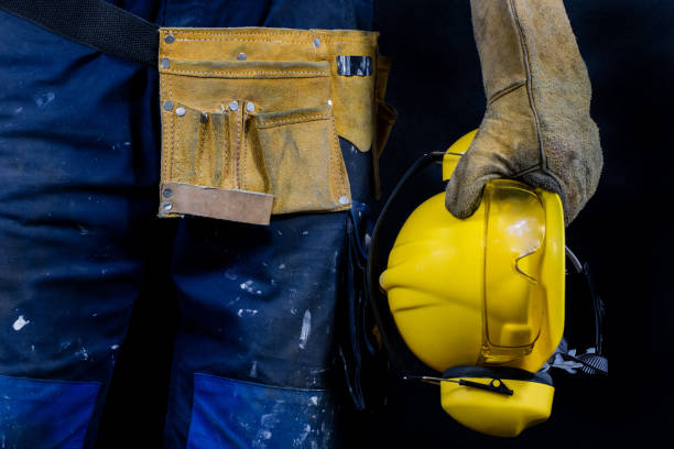 istock Workwear for production workers. A construction worker holding protective accessories. Black background. 910659382