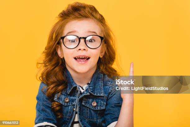 Portrait Of Smiling Little Kid In Eyeglasses Pointing Up Isolated On Yellow Stock Photo - Download Image Now