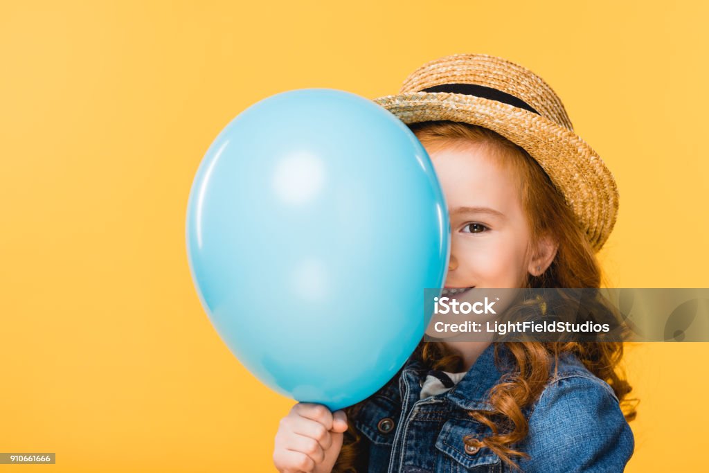 obscured view of smiling child covering face with balloon isolated on yellow Balloon Stock Photo