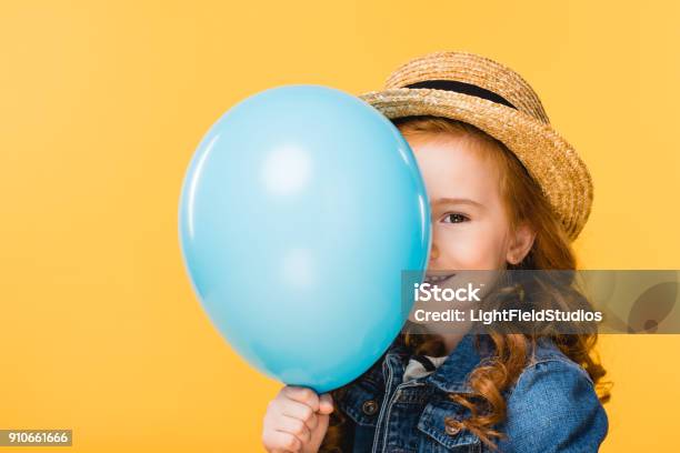 Obscured View Of Smiling Child Covering Face With Balloon Isolated On Yellow Stock Photo - Download Image Now