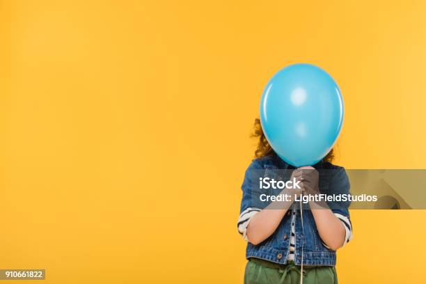 Obscured View Of Child Covering Face With Balloon Isolated On Yellow Stock Photo - Download Image Now