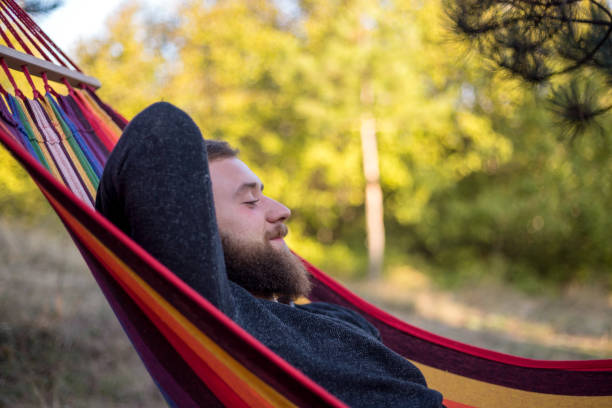 istock Caucasian man lying on hammock in a pine forest. Outdoors relaxation. 910666256
