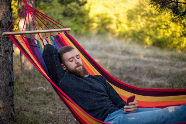 istock Caucasian man lying on hammock in a pine forest. Outdoors relaxation. 910667126