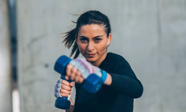 mujer joven de entrenamiento con pesas - posing looking at camera combative sport boxing fotografías e imágenes de stock