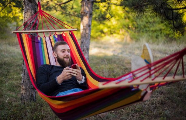 istock Caucasian man lying on hammock in a pine forest. Outdoors relaxation. 910668854