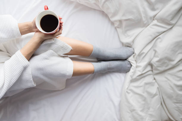 istock Close-Up Of Hand Holding Coffee Cup On Bed 910689826