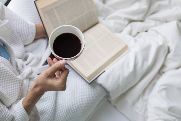istock Close-Up Of Hand Holding Coffee Cup On Bed 910690460