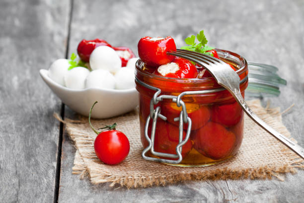 istock Marinated  cherry tomatoes stuffed with mozzarella and spices on wooden table 910694532