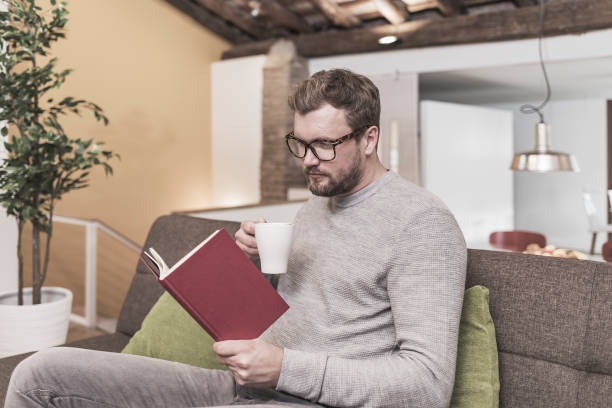 istock Man reading book at home 910694958