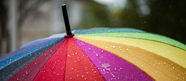 Panorama of close-up  umbrella in rainbow colors in rainy autumn day, blur focus